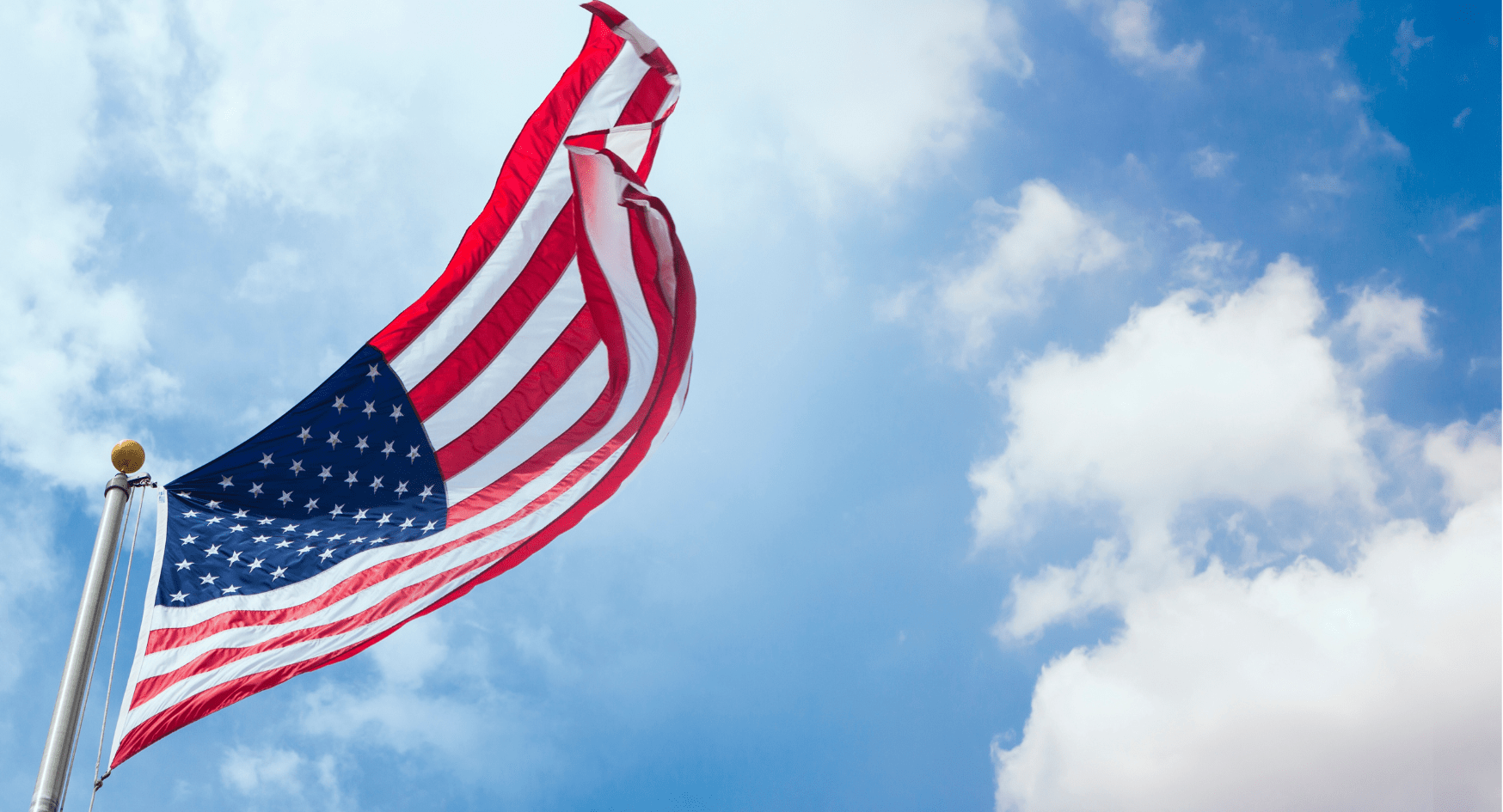 the american flag against a blue sky with clouds