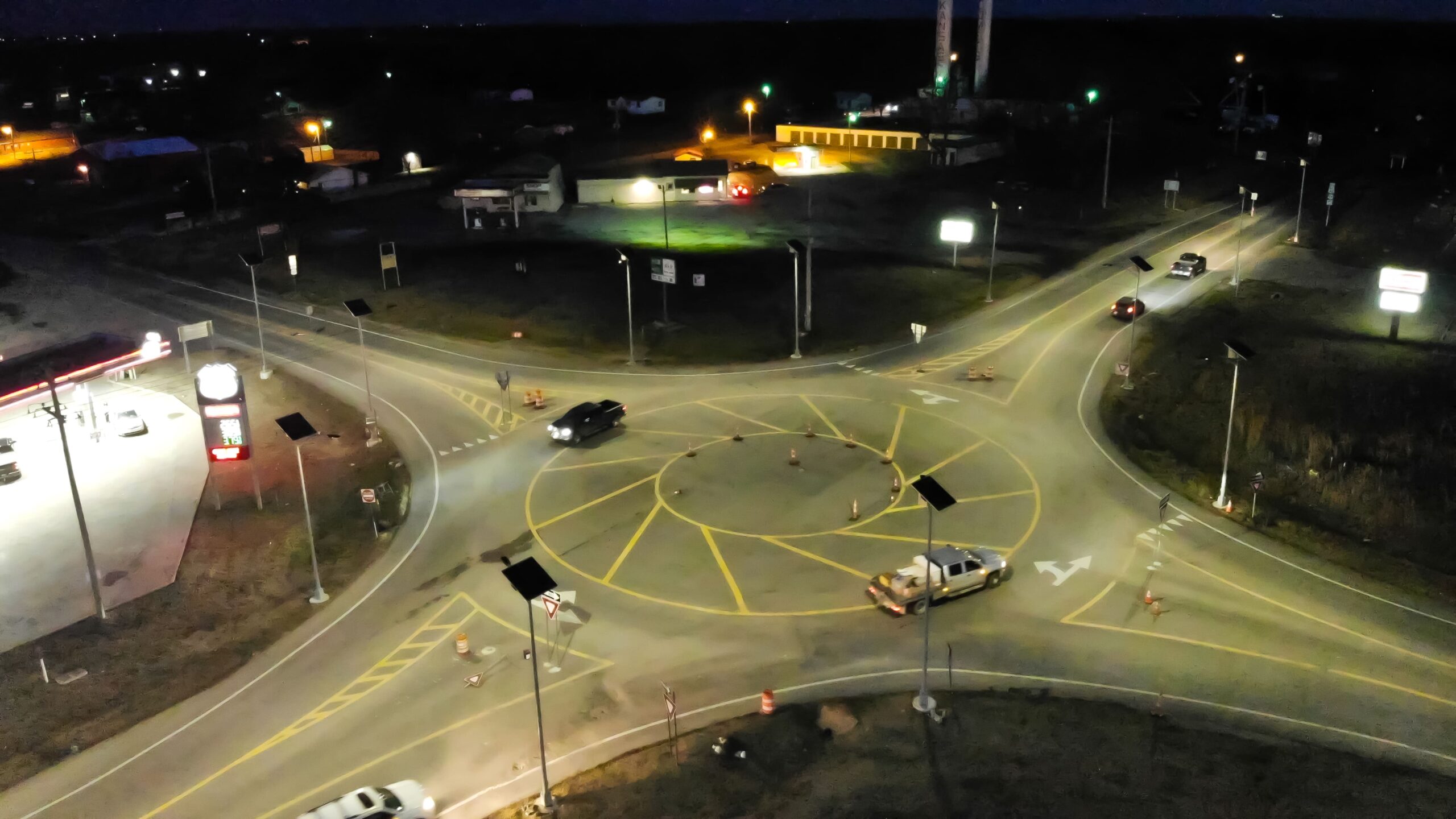 Traffic roundabout at night with vehicles and solar lighting systems
