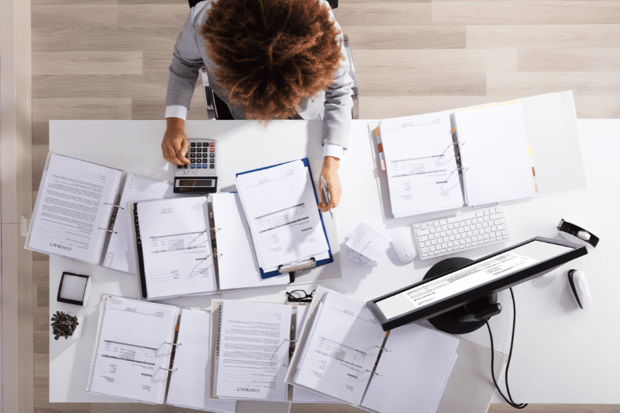 overhead view of person sitting at a desk with paperwork spread across it