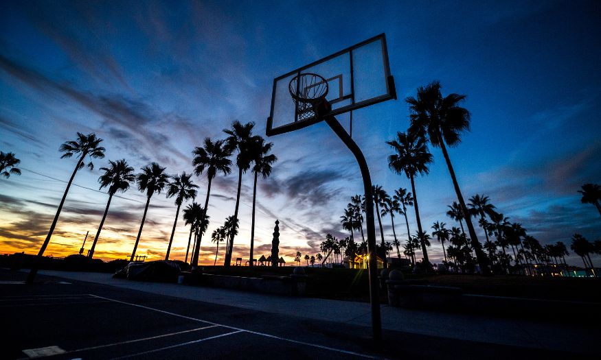 empty basketball court at dusk with palm trees